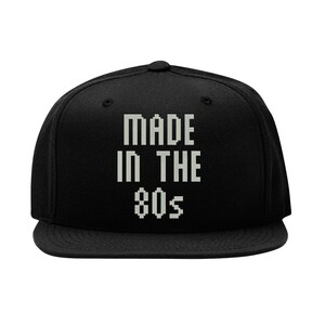 May include: Black baseball cap with white text that reads "MADE IN THE 80s".
