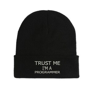 Può includere: Berretto nero con la scritta bianca "TRUST ME I'M A PROGRAMMER". Il berretto è un classico cappello in maglia a tinta unita, adatto per un abbigliamento casual. Il testo è centrato.
