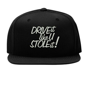 May include: Black baseball cap with the white text "DRIVE it like U STOLE it!" The cap features a flat peak and a structured crown. The text is in a handwritten style.