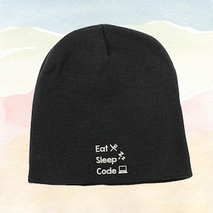 Puede incluir: Gorro negro con la frase blanca "Eat Sleep Code", acompañada de un tenedor, una nota musical y un icono de portátil. El gorro está hecho de tejido de punto.