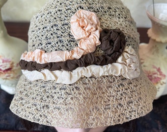 May include: A beige crochet hat with a wide brim and a decorative flower made of pink and brown fabric.