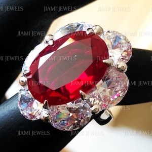 Può includere: Un anello d'argento con un grande rubino di forma ovale circondato da diamanti più piccoli.