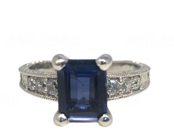 May include: A silver ring with a blue emerald-cut sapphire and a band of small diamonds.