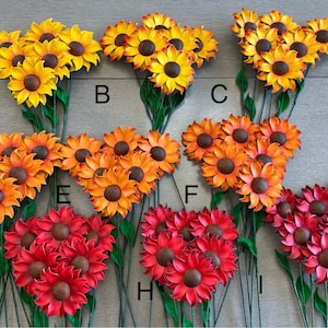 May include: Nine bunches of faux sunflowers with wire stems. Each bunch has 10-12 flowers. The flowers are in shades of yellow, orange, and red.