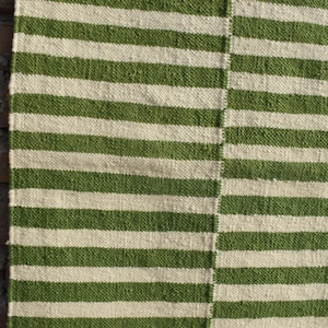 May include: Green and white striped woven rug with a textured surface.