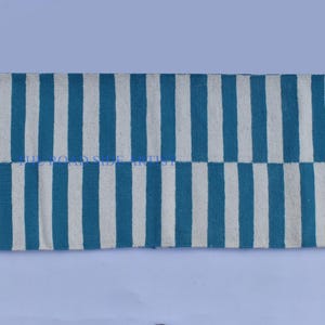 May include: A blue and white striped rug with fringe on the ends. The rug is made of cotton and is perfect for adding a touch of color to any room.