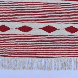 May include: A woven rug with a red and white striped pattern. The rug features a series of red diamond shapes along the center and a fringe along the bottom edge. The rug is made of a textured material.