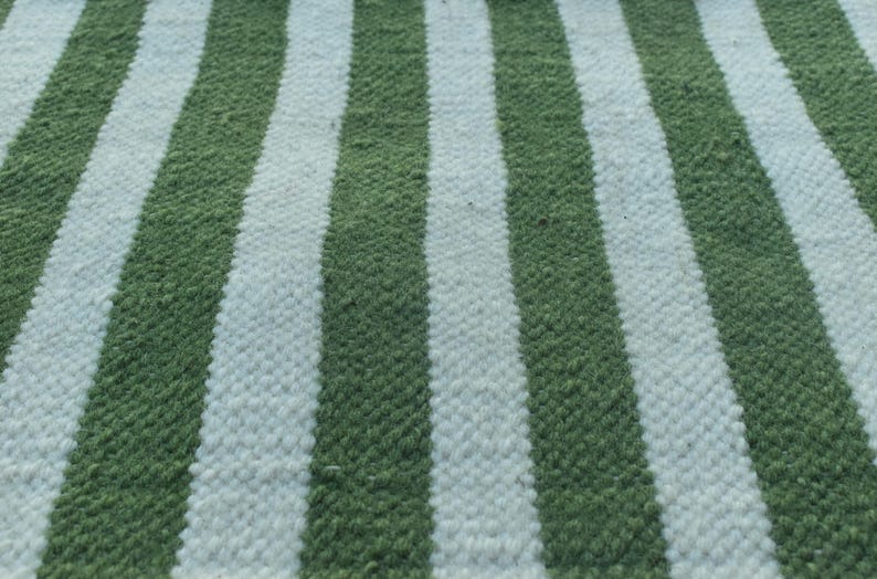 May include: A close-up of a green and white striped fabric. The fabric is woven with a textured pattern.