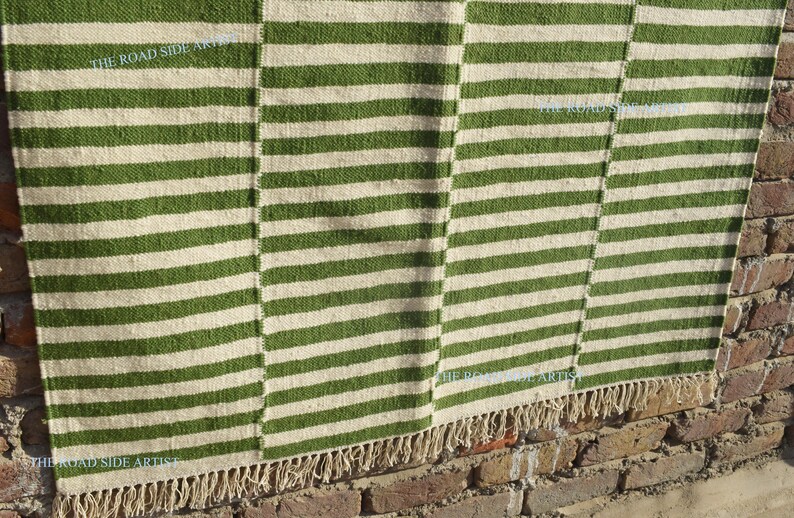 May include: A green and white striped rug with a fringe border. The rug is made of natural fibers and has a rustic look.