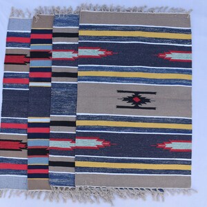 Puede incluir: Cuatro alfombras tejidas con un patr&oacute;n a rayas en tonos de azul, rojo, amarillo y beige. Las alfombras tienen flecos en los bordes.