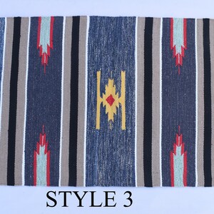 Puede incluir: Una alfombra rayada azul, gris y beige con un patr&oacute;n geom&eacute;trico en el centro. La alfombra tiene flecos en todos los lados. El texto "STYLE 3" est&aacute; impreso debajo de la alfombra.