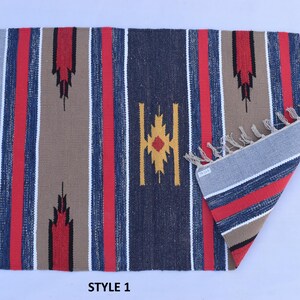 Puede incluir: Una alfombra tejida a mano con un patr&oacute;n a rayas en tonos de azul, rojo, marr&oacute;n y blanco. La alfombra tiene un dise&ntilde;o geom&eacute;trico en el centro y flecos en todos los lados. La alfombra est&aacute; etiquetada como "STYLE 1".