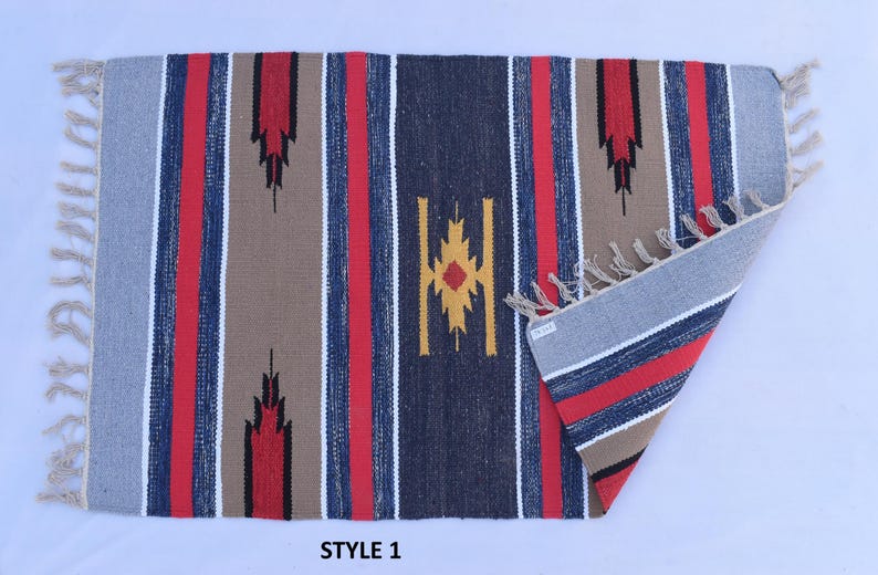 Puede incluir: Una alfombra tejida a mano con un patr&oacute;n a rayas en tonos de azul, rojo, marr&oacute;n y blanco. La alfombra tiene un dise&ntilde;o geom&eacute;trico en el centro y flecos en todos los lados. La alfombra est&aacute; etiquetada como "STYLE 1".
