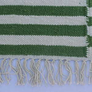 May include: Green and white striped rug with a fringe border.
