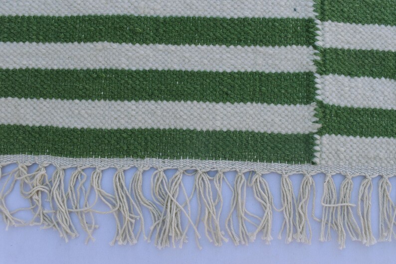 May include: Green and white striped rug with a fringe border.