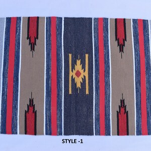 Puede incluir: Una alfombra rayada con un patr&oacute;n geom&eacute;trico en el centro. La alfombra tiene rayas rojas, azules y beige con un borde blanco. El patr&oacute;n geom&eacute;trico est&aacute; en tonos de amarillo, rojo y azul. La alfombra est&aacute; etiquetada como "STYLE-1".