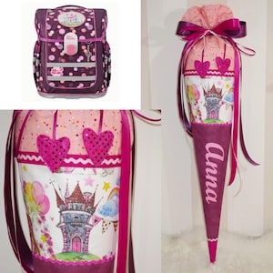Könnte beinhalten: Ein rosa-lilafarbener Schulranzen mit einem Schloss-Design und ein passender rosa-lilafarbener Schultüte mit dem Namen "Anna" darauf. Die Schultüte ist mit rosa Herzen und einem Schloss-Design verziert.