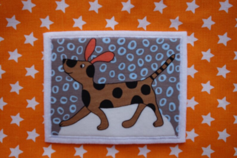 May include: A brown and black spotted dog with orange ears is on a grey background with blue and white circles. The dog is looking to the left.