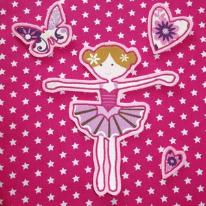 May include: Appliqu&eacute; set featuring a ballerina, butterfly, and hearts on a pink star-patterned background. The ballerina is in a ballet pose, wearing a pink tutu. The butterfly and hearts have floral patterns.