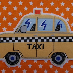 Puede incluir: Un taxi de juguete amarillo con una franja de cuadros negros y blancos, la palabra "TAXI" impresa en el lateral y una luz roja en la parte superior.