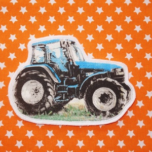 Puede incluir: Un tractor azul con un borde blanco alrededor de la imagen. El tractor está en un campo verde con un fondo blanco.