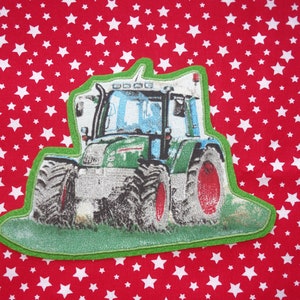 Op de afbeelding: Groene en blauwe tractor-applicatie met een groene rand op een rode achtergrond met witte sterren.