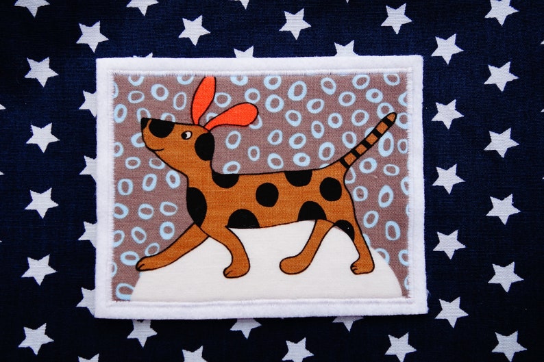 May include: A brown and black spotted dog with orange ears is walking on a white background with a brown and blue patterned border. The dog is surrounded by white circles on a brown background.