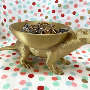 May include: A gold-painted animal figurine with a bowl on its back. The bowl is filled with various rings and jewellery.