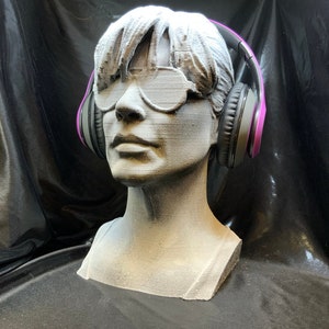 May include: A 3D printed bust of a person wearing sunglasses and purple headphones.