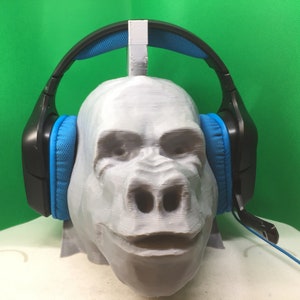 Könnte beinhalten: Ein 3D-gedruckter Gorillakopf mit einem schwarzen Kopfhörer mit blauen Ohrmuscheln. Der Kopfhörer liegt auf den Ohren des Gorillas.