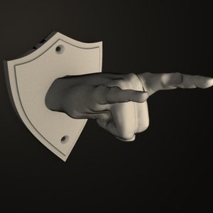 May include: A white, shield-shaped wall mount with a sculpted hand pointing to the right. The hand is made of a light gray material.