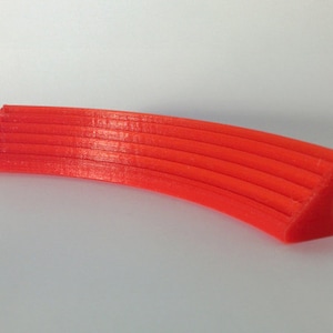 May include: A bright orange 3D printed curved shelf with a series of parallel ridges.