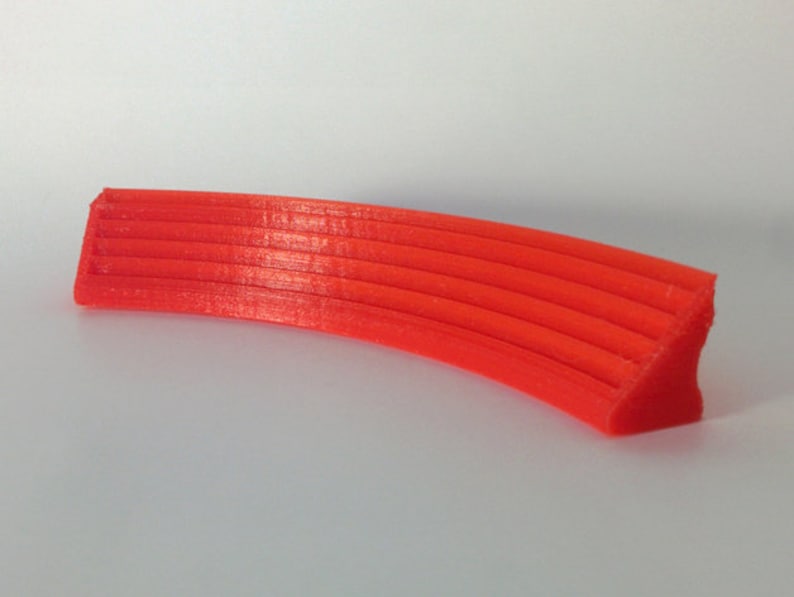 May include: A bright orange 3D printed curved shelf with a series of parallel ridges.