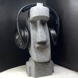 以下が含まれることがあります： 黒いヘッドホンを耳につけた灰色の石の彫刻の頭部
