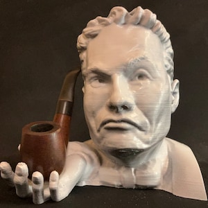 Peut inclure: Un buste en 3D imprimé en blanc d'une personne avec une expression sérieuse, tenant une pipe en bois brun dans sa main.