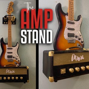 May include: A black and gold electric guitar amplifier mounted on a wall with a guitar hanging above it. The amplifier has a gold grill and knobs and the text "M3g3d" written on it. The guitar is a sunburst color with a white pickguard and has a black strap hanging from it.