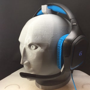 May include: Black gaming headset with blue accents and a microphone. The headset is on a white 3D printed head.