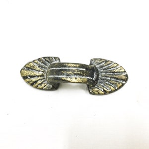 May include: A gold and silver metal decorative hardware piece with a fan-shaped design on each end.