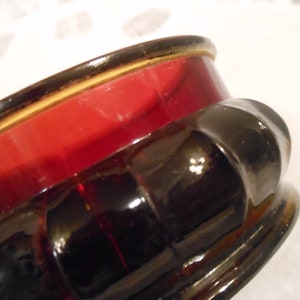 May include: A red and black glass bowl with a fluted design. The bowl has a shiny, glossy finish.