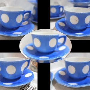 May include: A set of blue teacups and saucers with white polka dots. The cups have a handle and sit on matching saucers. The edges of the saucers have a scalloped design. The set is ideal for serving tea.