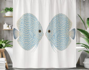 May include: White shower curtain featuring two blue discus fish facing each other. The fish have intricate patterns in a lighter blue and beige. The curtain is hanging in a bathroom setting with plants and a bathtub.