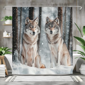 May include: A shower curtain featuring two gray wolves in a snowy forest scene. The wolves are sitting in the snow, with a backdrop of tall, blurred trees and falling snowflakes. The curtain adds a nature-inspired touch to any bathroom.