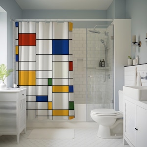 May include: A white shower curtain with a Mondrian-style design. The design features a grid of black lines with blocks of red, blue, yellow, and green. The curtain is hanging in a bathroom with white fixtures and a light blue wall.