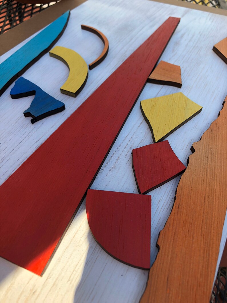 May include: Abstract art wall decor made of wood with geometric shapes in shades of blue, yellow, orange, and red.