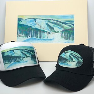 May include: Two black trucker hats with a white mesh back. One hat has a full-color image of a snowy mountain scene printed on the front. The other hat has a smaller, oval-shaped image of the same scene on the front.