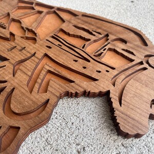 May include: A wooden wall decor in the shape of a bear with intricate cutouts. The bear is brown and has a detailed face.