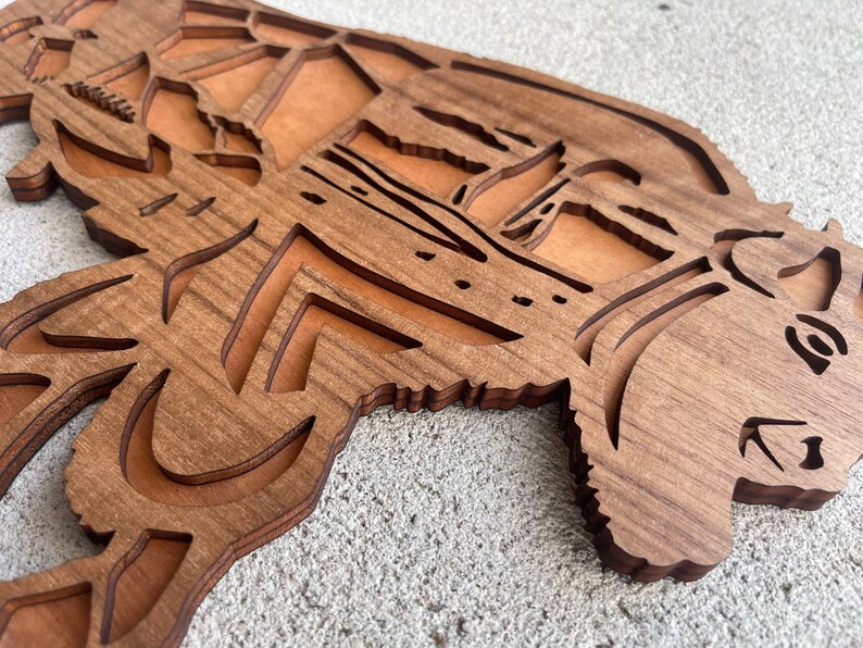 May include: A wooden wall decor in the shape of a bear with intricate cutouts. The bear is brown and has a detailed face.