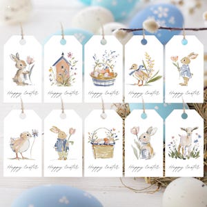 Puede incluir: Diez etiquetas de regalo blancas con ilustraciones de acuarela con temas de Pascua. Cada etiqueta presenta un diseño diferente, incluyendo conejitos, pollitos, cestas de huevos y un patito. La frase "Happy Easter" está impresa en cada etiqueta.