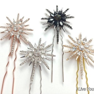 May include: Four hair clips with starburst designs. The clips are silver, gold, rose gold, and black. Each clip has a starburst design with rhinestones.