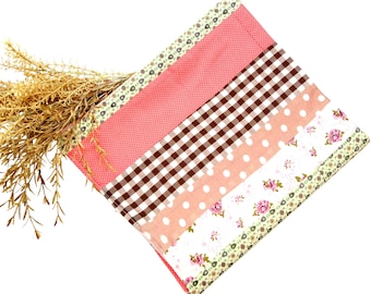 May include: A patchwork fabric item with a variety of patterns, including pink polka dots, brown gingham, and floral prints. The item is decorated with a floral patterned trim and contains dried wheat stalks.